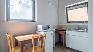 Eine kompakte Küche mit Mikrowelle, kleinem Kühlschrank, Spüle und einem Esstisch mit Stühlen.
