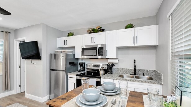 A modern kitchen with white cabinets, stainless steel appliances, and a granite countertop.