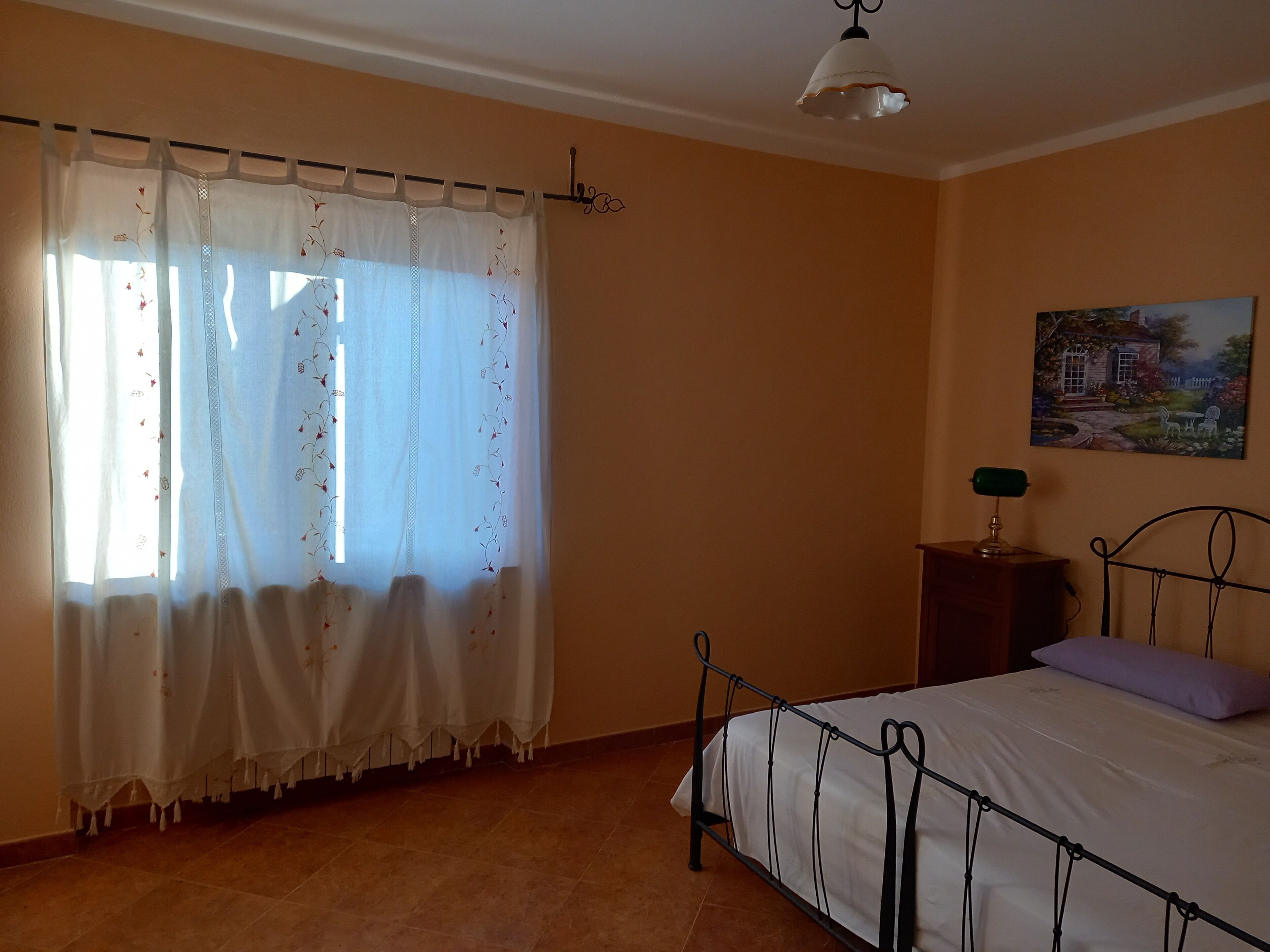Un dormitorio con una cama, una mesita de noche, una lámpara y un cuadro en la pared.