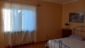 Un dormitorio con una cama, una mesita de noche, una lámpara y un cuadro en la pared.