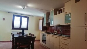 Uma cozinha com mesa e cadeiras, armários, fogão e geladeira.