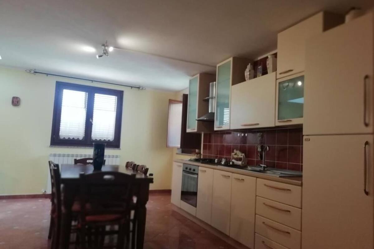 A kitchen with a dining table and chairs, cabinets, a stove, and a refrigerator.