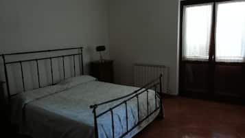 A bedroom with a metal bed frame, a radiator, and a window with blinds.