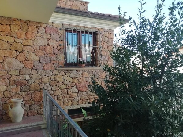 Ein Steinhaus mit Fenster, einer kleinen Veranda und einem Blumentopf.