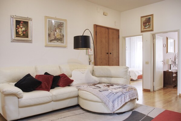 Un salon avec un canapé en cuir blanc, une porte en bois et une lampe.