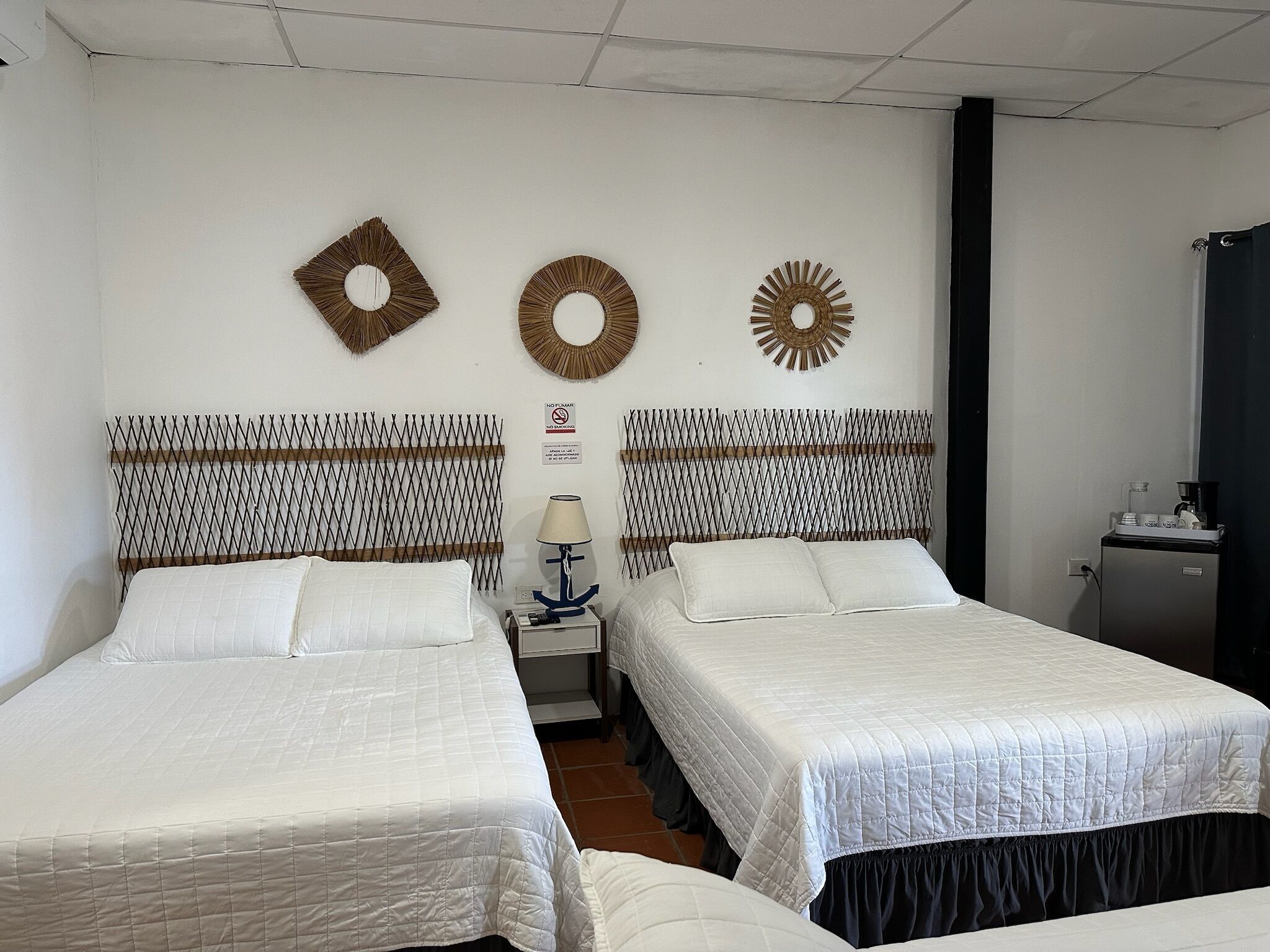 Habitación de hotel con dos camas, una mesita de noche con lámpara y decoración en la pared.