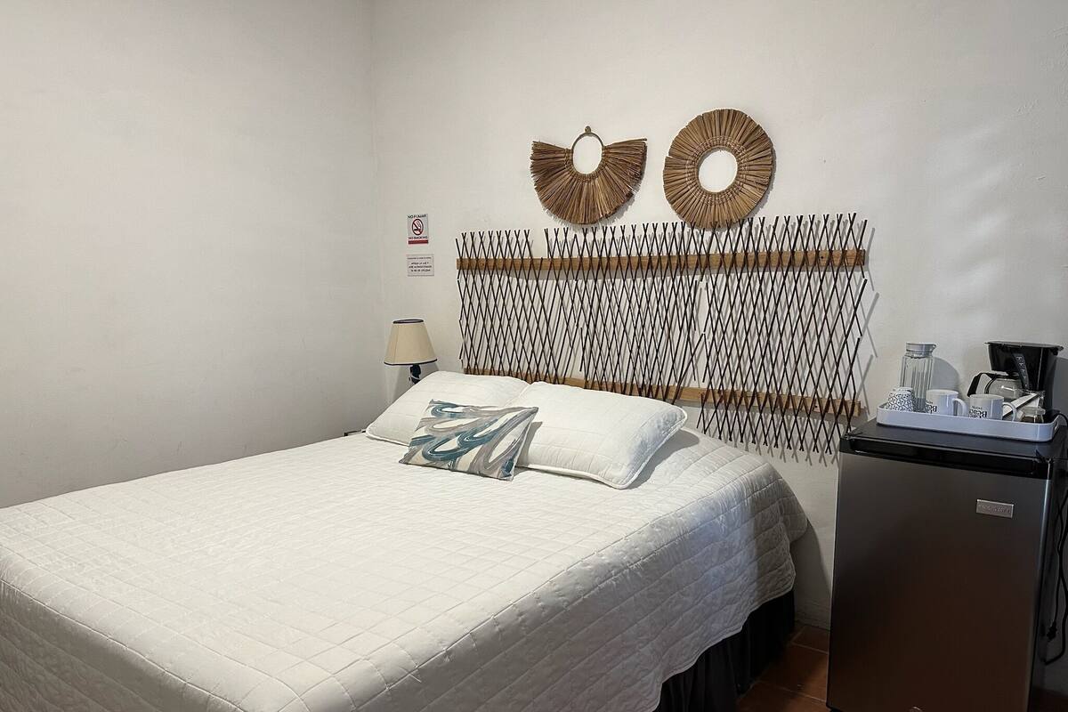 A hotel room with a bed, a small refrigerator, and decorative wall art.
