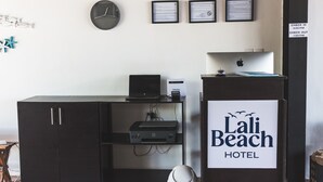 Taulell de recepció amb un ordinador, una impressora i un cartell de l'Hotel Lali Beach.