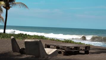 Ubicación a pie de playa, arena negra y sombrillas