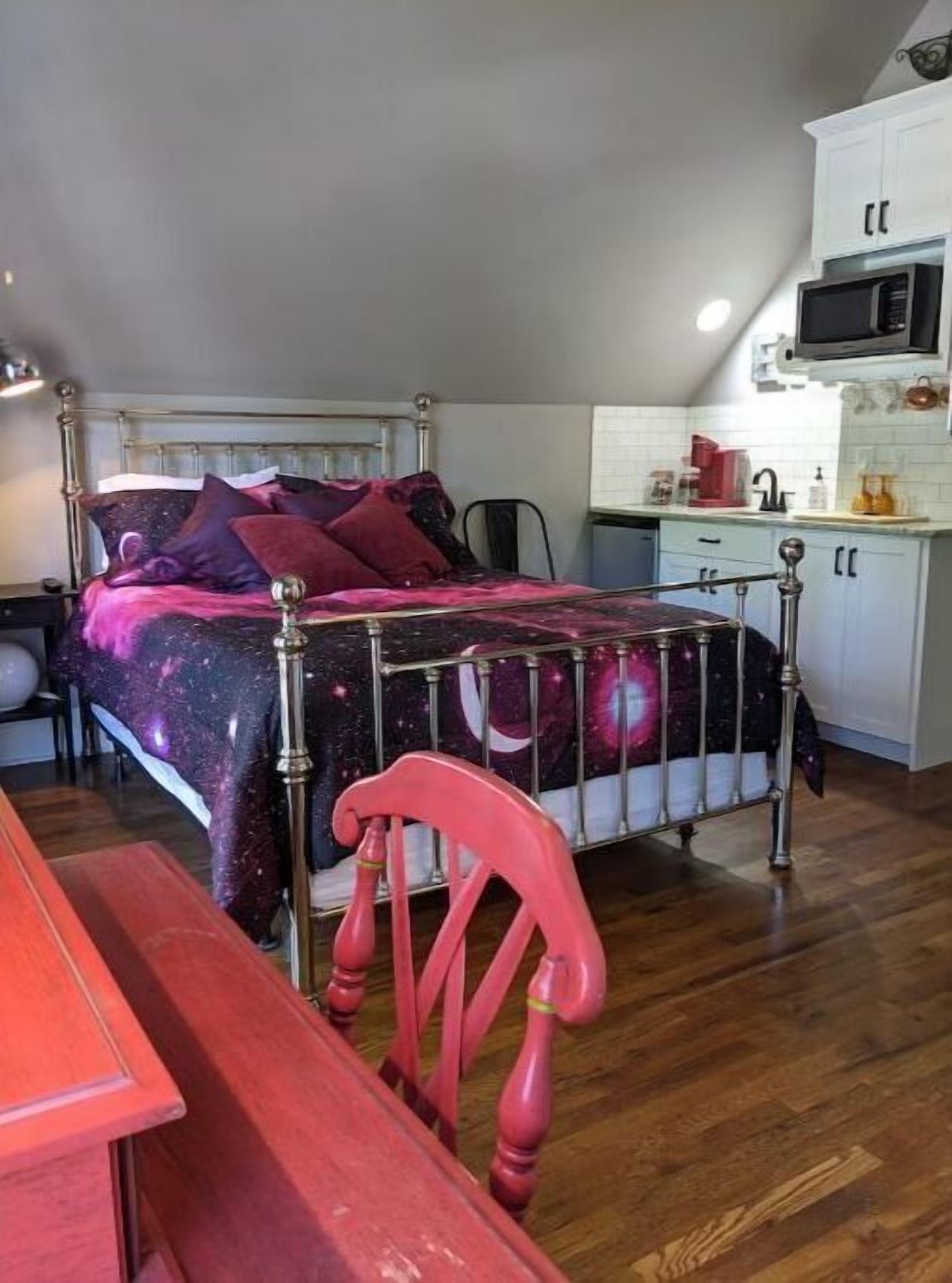 Un dormitorio con cama, escritorio, silla y kitchenette.
