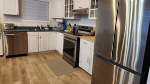 Une cuisine avec des meubles blancs, des appareils électroménagers en acier inoxydable et un plancher en bois.