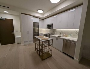 Kitchen features a central island with a glass top and a stove, microwave, and sink.