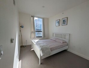 Cozy retreat with a single bed, framed pictures, and a window with curtains.