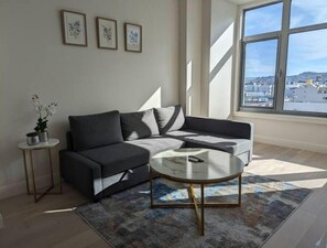 Relax in this stylish living room with a sofa, coffee table, and city views.