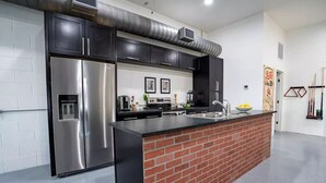 A modern kitchen with stainless steel appliances, a brick accent wall, and a clean, white interior. - Kerrville Texaco
 (Kerrville)