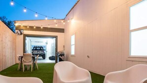 A backyard with artificial grass, white plastic chairs, and string lights. - Kerrville Texaco
 (Kerrville)