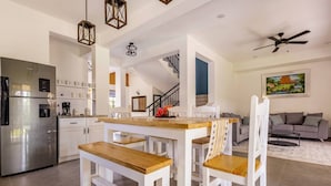 Una cocina moderna con refrigerador de acero inoxidable, mesa de comedor de madera y sillas blancas.