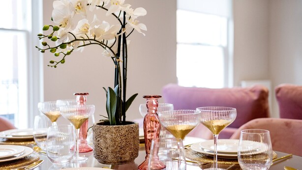 A dining table set with white plates, gold cutlery, and pink glassware. - Marble Arch Suite 3-Hosted by Sweetstay (London)