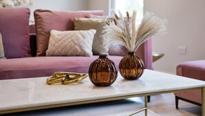 A modern living room with a pink sofa, two decorative vases, and a gold ring on a marble coffee table. - Marble Arch Suite 3-Hosted by Sweetstay (London)