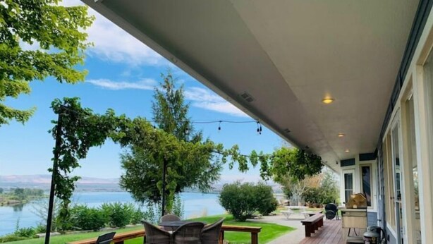 A covered patio with outdoor furniture, a view of a lake, and a clear sky. - Columbia River Waterfront with Private Dock near Gamble Sands Golf Course! (Brewster)