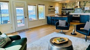 A modern kitchen with a bar area, large windows, and a cozy seating area with a fireplace. - Columbia River Waterfront with Private Dock near Gamble Sands Golf Course! (Brewster)