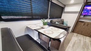 Un espace de vie compact comprenant un coin cuisine, un espace repas avec une table et des chaises, un canapé et un téléviseur.