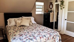 Un dormitorio con cama, cómoda, ventana y puerta.
