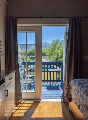 A bedroom with a view of a pool and mountains.