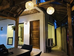 A dining area with a table and chairs, a wooden door, and a hanging light fixture. - Tahanan Homestay (General Luna)