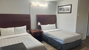 Una habitación de hotel con dos camas, una mesita de noche, una lámpara y un cuadro en la pared.
