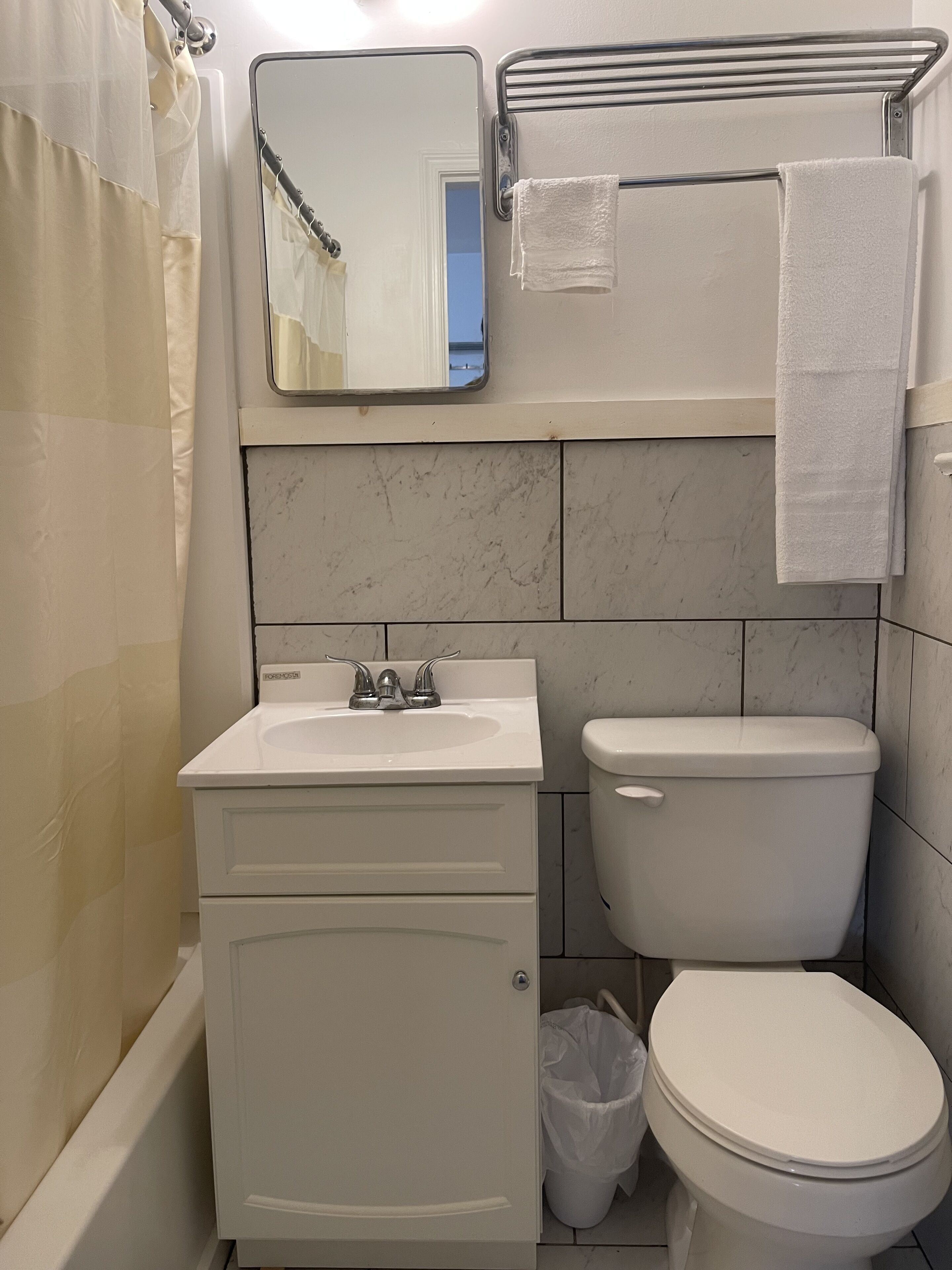 Une salle de bain avec un lavabo blanc, des toilettes et un rideau de douche.