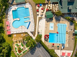 Vue aérienne d’un complexe hôtelier doté de plusieurs piscines, de chaises longues et de parasols.