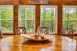 A gathering room with a wooden table, chairs, and a sign above the windows.