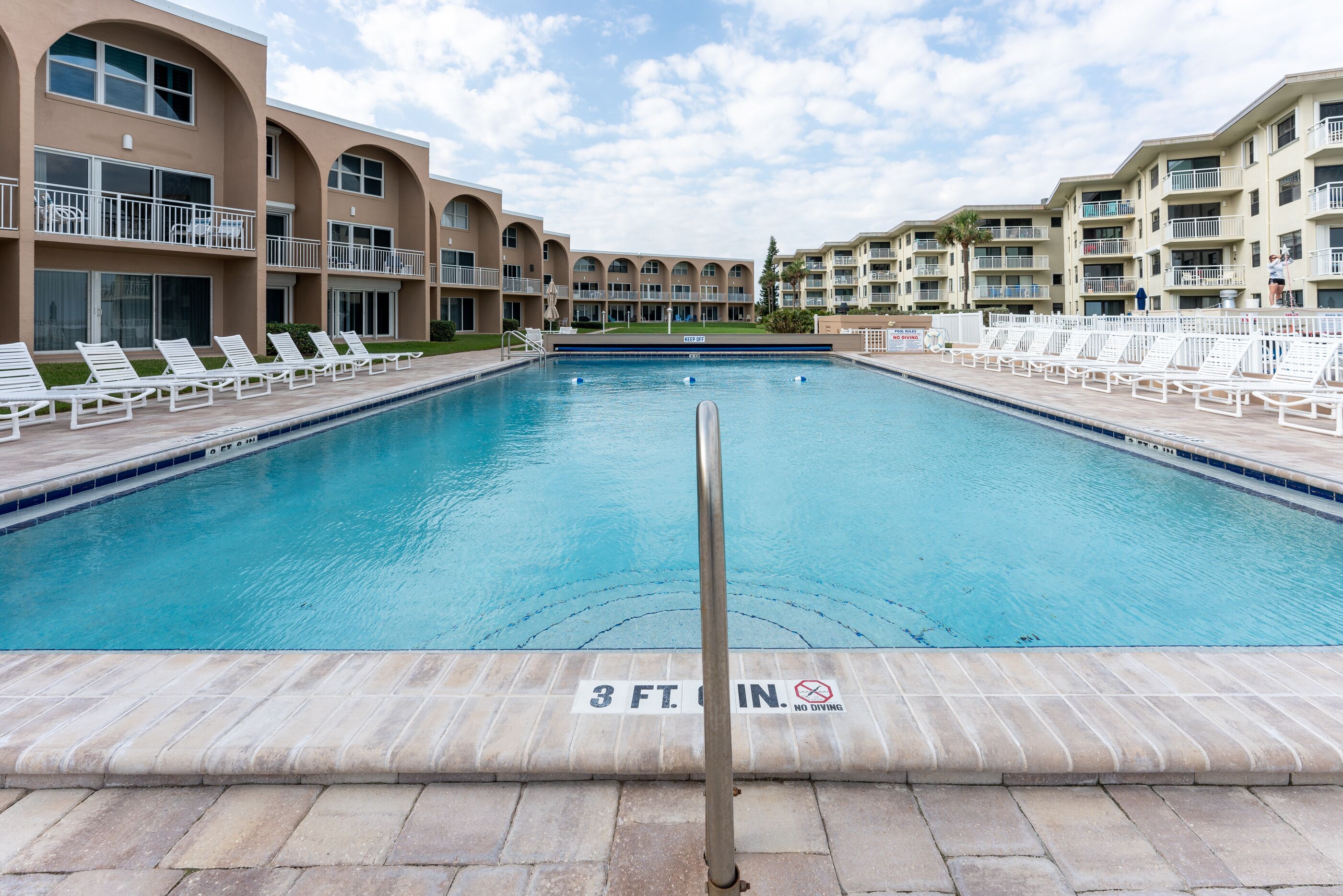 A swimming pool with lounge chairs and a sign indicating a 3-foot depth limit.