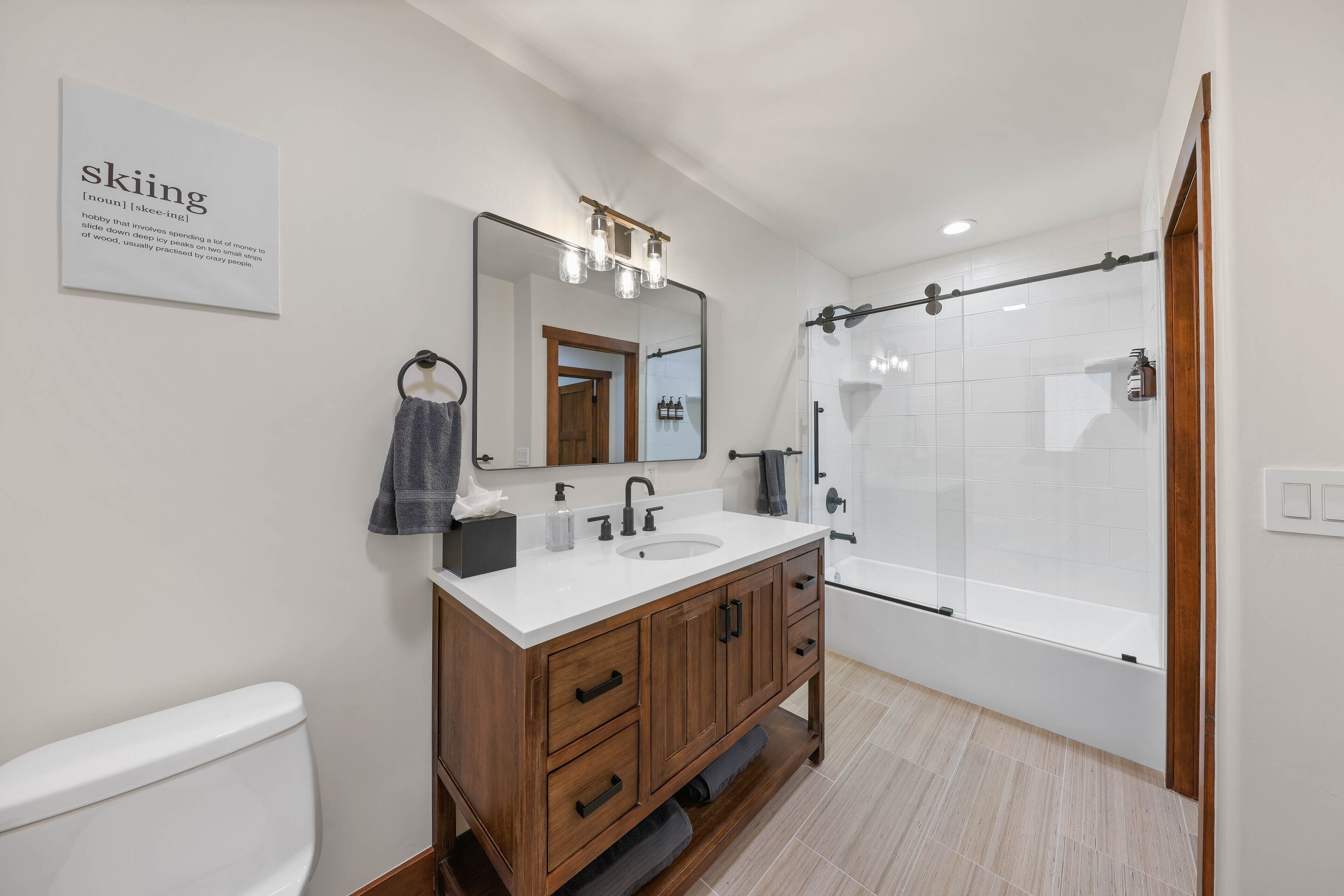 Un baño moderno con tocador de madera, un espejo grande y mampara de ducha de vidrio.