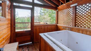 A wooden cabin with a large wooden bathtub, a wooden deck, and a view of a forested area. - Jenny Creek Cabin w/ Jacuzzi and Wood Stove at Green Springs Inn (Ashland)