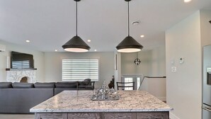 Una cocina moderna con una isla central, armarios de madera oscura e iluminación colgante.