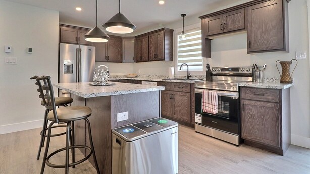 Una cocina moderna con armarios de madera oscura, electrodomésticos de acero inoxidable e iluminación colgante.