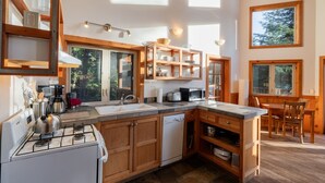 A modern kitchen with wooden cabinets, a gas stove, a dishwasher, and built-in shelves.