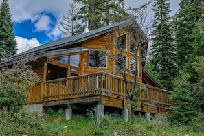 A wooden cabin with a balcony, surrounded by trees.
