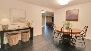 A dining area with a round table and chairs, a console table with baskets, and a painting on the wall. - The Charming Home with a Pool (Yuba City)