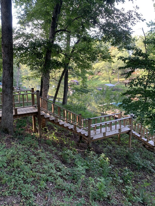 Una escalera de madera que asciende por una colina, rodeada de árboles y vegetación.