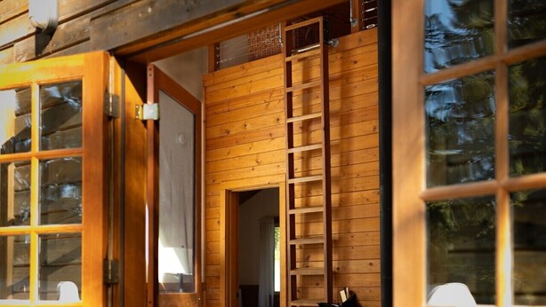 A wooden cabin with a large open door, a white chair, a ladder, and a fireplace. - Chinquapin Mountain Cabin w/ Jacuzzi and Wood Stove at Green Springs Inn (Ashland)