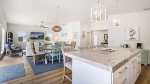 A spacious living area with a large island, dining table, and seating arrangements. - Dock Holiday: On Canal, Pool & Spa by Anna Maria Life Vacation Rentals (Anna Maria)
