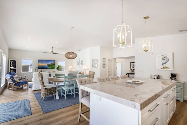Amplia sala de estar con una isla grande, mesa de comedor y disposición de asientos.