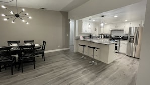 A modern kitchen with white cabinets, stainless steel appliances, and a central island with bar stools.