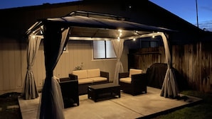 A covered patio area with a sofa, chairs, and a table.