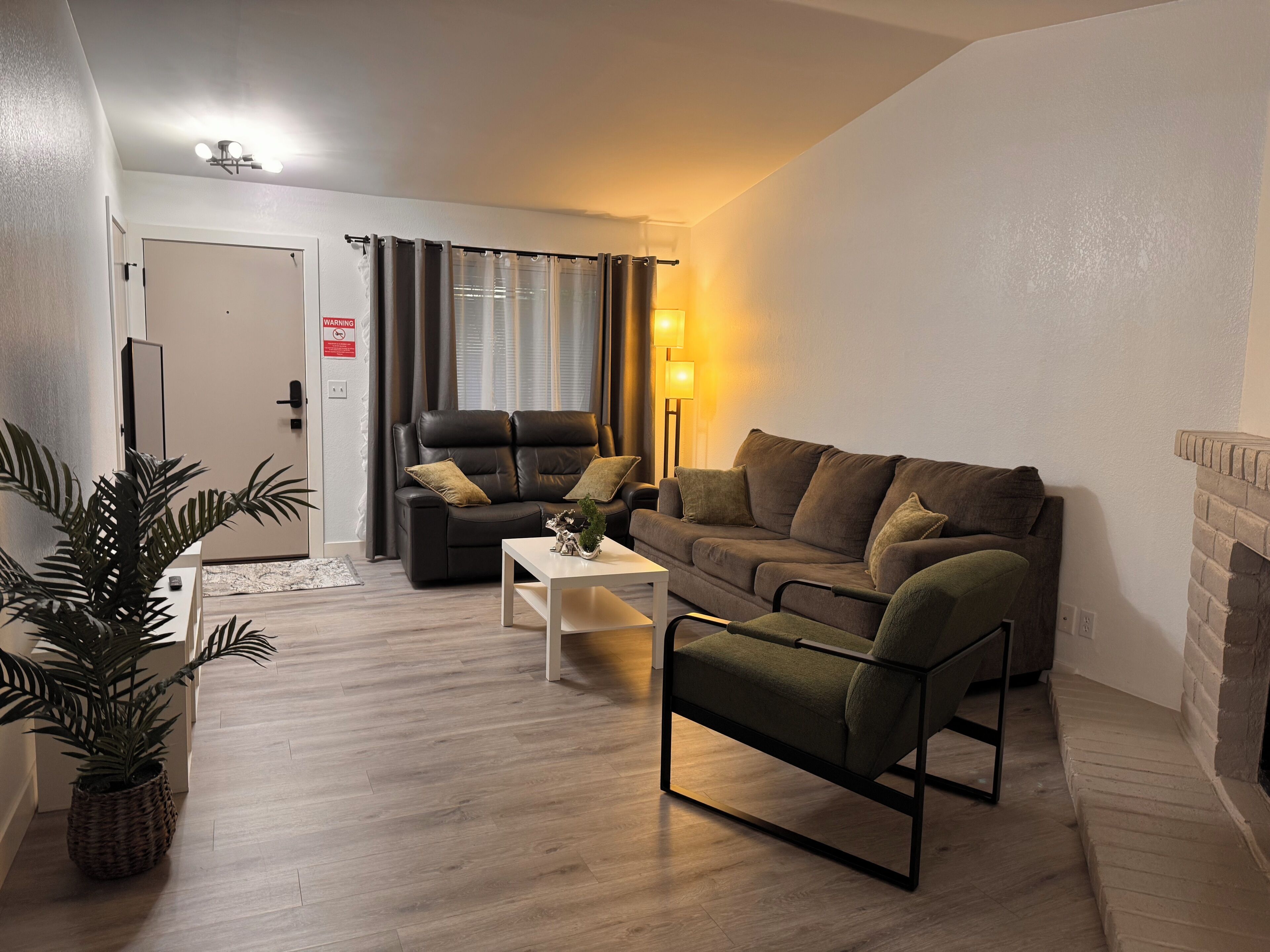 Ein Wohnzimmer mit Sofa, Sesseln, Couchtisch und Kamin.