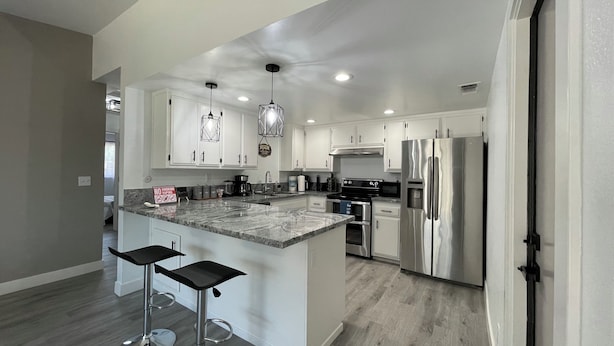 A modern kitchen with white cabinets, stainless steel appliances, and a marble countertop.