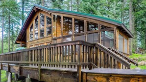 A wooden cabin with a deck and stairs leading to the entrance.
